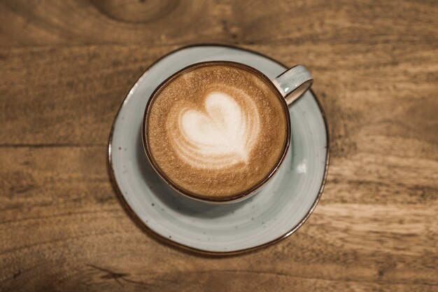 Beautiful cup of coffee with a heart shape on a wooden background. Place for your text. Valentine's day concept. Selective focus.