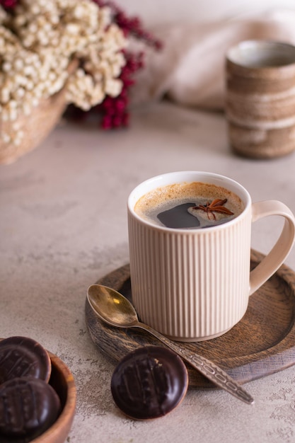 Beautiful cup of coffee on wooden table with chocolate cookies. pastel tone. Vertical