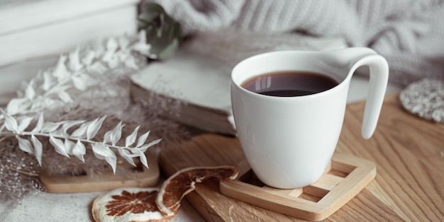 Una bella tazza con tè o caffè su un supporto in legno. concetto di comfort domestico.