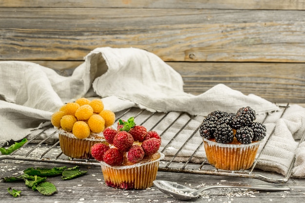 beautiful cupcakes with berries on wooden background