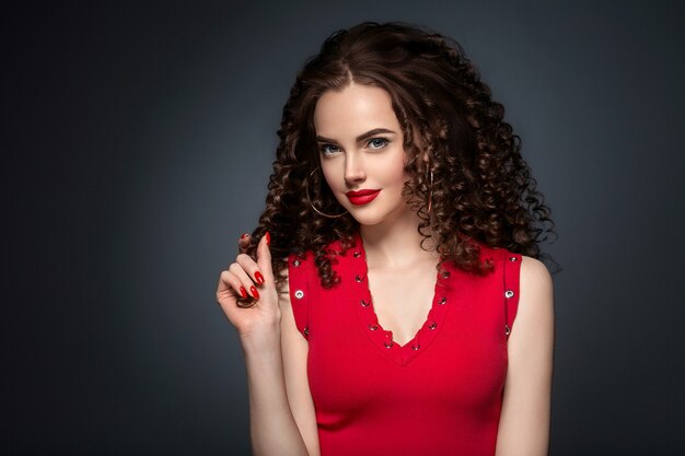 Bei capelli ricci femminili in rosso con labbra rosse e manicure vestito, acconciatura afro rossa di bellezza. colpo dello studio.