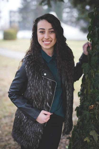 Beautiful curly Bosnian Caucasian woman in a black leather jacket posing outside