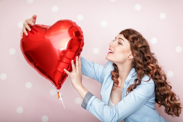 Bella donna riccia con palloncini d'aria a forma di cuore per san valentino