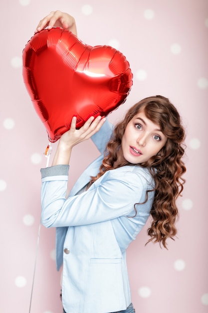 Beautiful curly woman with heart shaped air balloons for St Valentine's Day