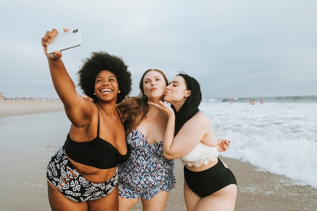 Belle donne curvy prendendo un selfie in spiaggia