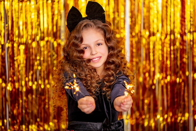Beautiful cute cheerful child girl on a Golden holiday background with sparklers in her hands