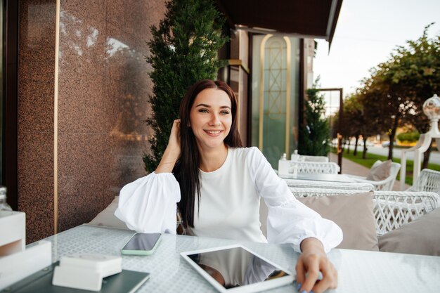 A beautiful cute girl in a cafe drinks coffee at a table.