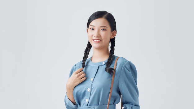 Beautiful cute girl having fun and holding pigtails posing near white wall