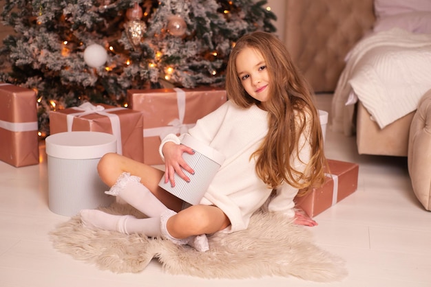 beautiful cute girl with gifts near the christmas tree at home