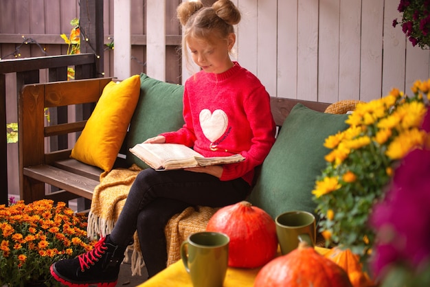 beautiful cute little girl in autumn sits outdoors