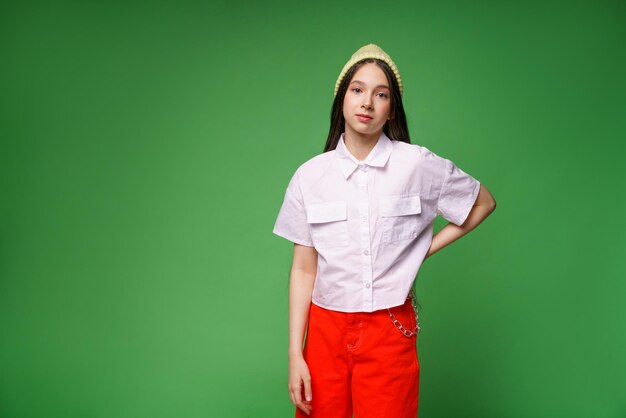 Beautiful cute millennial girl in hat and white shirt and in red pants isolated