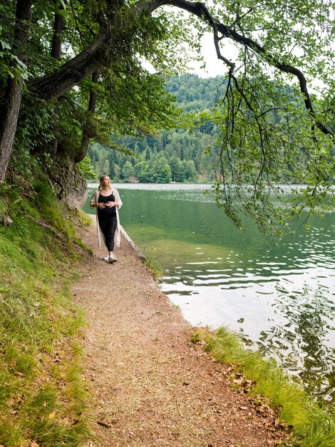 Beautiful, cute pregnant woman near a mountain lake in the forest.