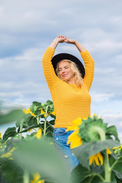 Beautiful cute sexy girl in a yellow sweater jeans and a black hat