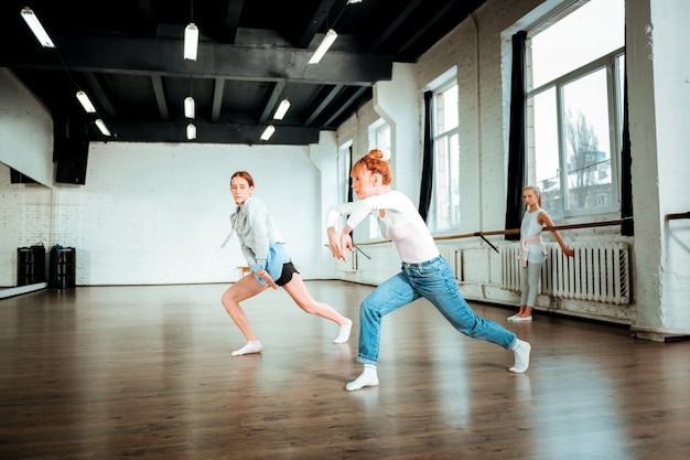 Beautiful dance. Professional ballet teacher wearing blue jeans and her student moving beautifully