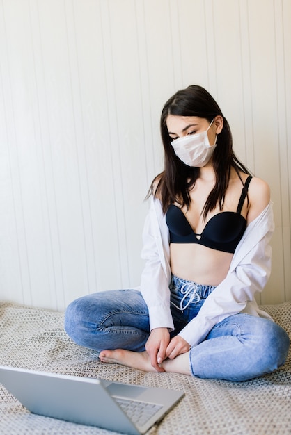 Beautiful dark-haired female wearing protective mask working at home