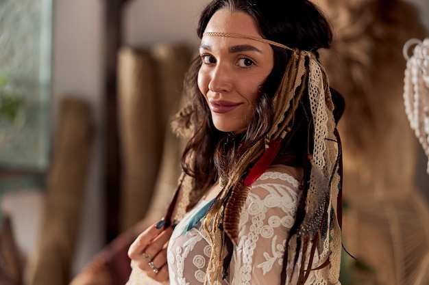 Beautiful dark haired woman in shamanic ethnic outfit in bali style decorated room