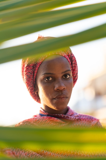 Photo beautiful dark skin young woman between palm branches on beach photo