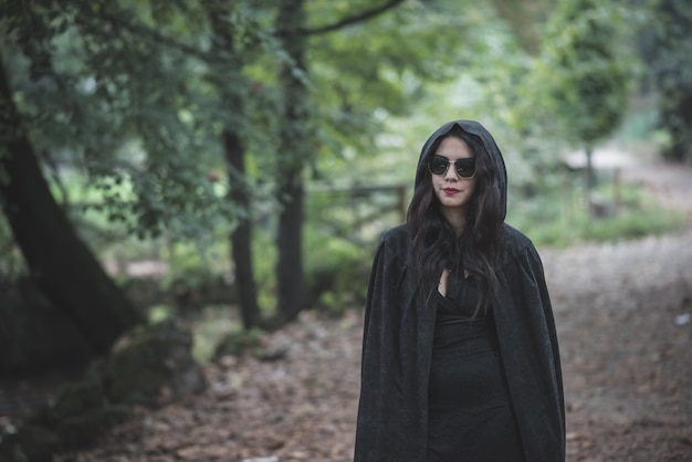 Bella donna vampiro scuro con mantello nero e cappuccio