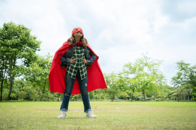 On a beautiful day in the park a young girl enjoys her vacation Playful with a red superhero costume