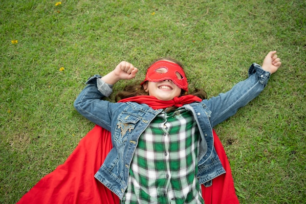 On a beautiful day in the park a young girl enjoys her vacation Playful with a red superhero costume