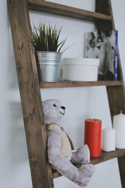 Beautiful decor on the shelf. soft toy, candles and a pot of\
flowers on a shelf at home.