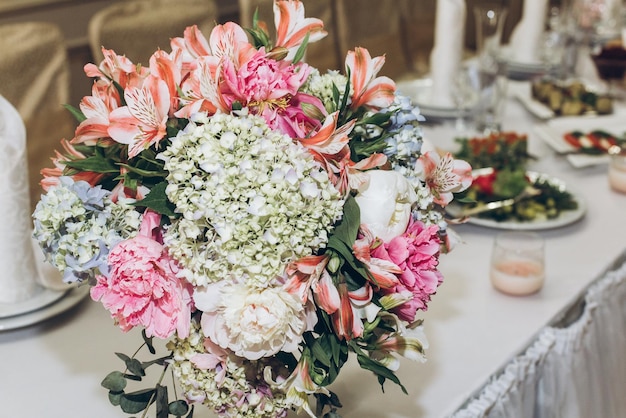 写真 レストランのスタイリッシュな装飾と装飾の豪華な結婚披露宴で、花瓶と緑にアジサイのブーケを持つ美しい装飾が施された目玉テーブル