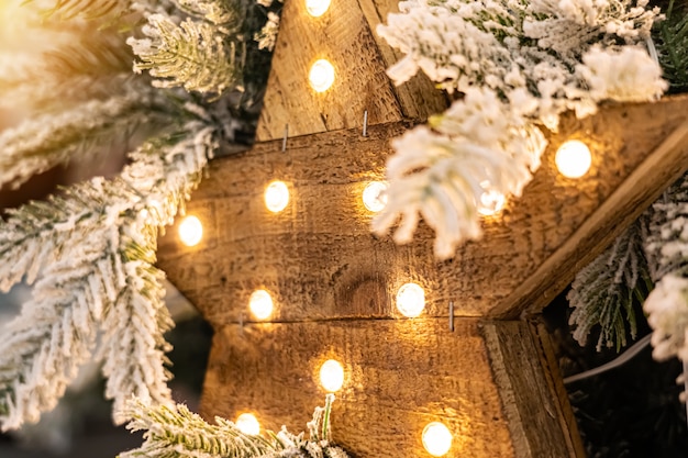 Beautiful decorative wooden star with lamps hanging on pine branches