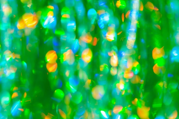 Beautiful defocused green bokeh lights background of holographic foil for your festive project