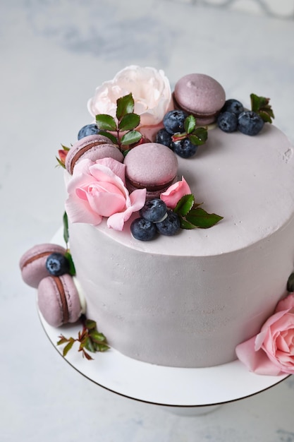 女の子のための美しく繊細なケーキ。デザートは、新鮮なブルーベリー、バラ、マカロンケーキで飾られています。