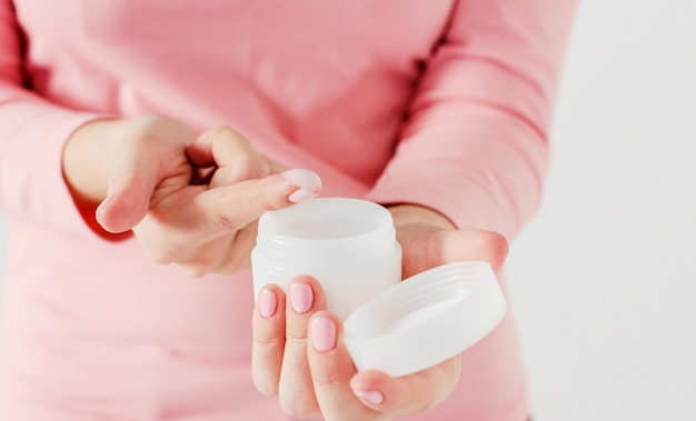 Beautiful delicate women's hands with pink manicure holding jar 