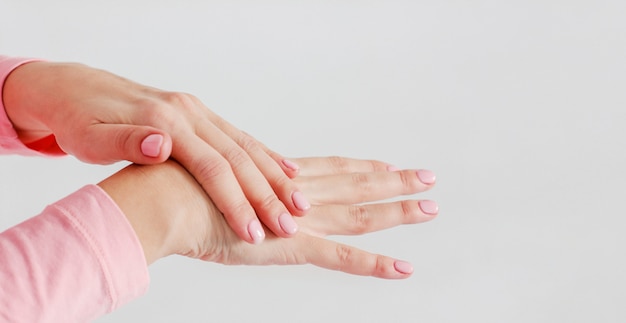 Le mani delle belle donne delicate con il manicure rosa sbavano il carin