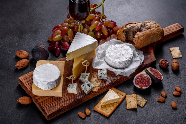 Beautiful delicious camembert cheese, parmesan, brie with grapes and figs on a wooden board. Snacks for wine on holiday