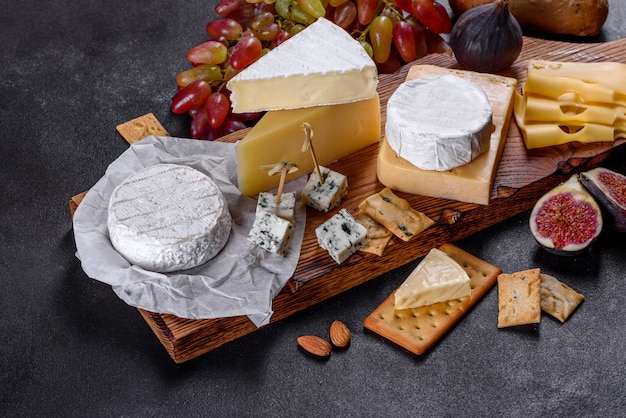 Beautiful delicious camembert cheese, parmesan, brie with grapes and figs on a wooden board. Snacks for wine on holiday