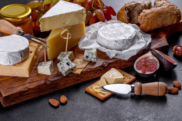 Beautiful delicious camembert cheese, parmesan, brie with grapes and figs on a wooden board. Snacks for wine on holiday