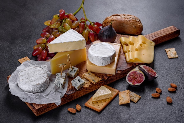 Beautiful delicious camembert cheese, parmesan, brie with grapes and figs on a wooden board. Snacks for wine 