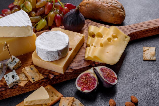 Beautiful delicious camembert cheese, parmesan, brie with grapes and figs on a wooden board.