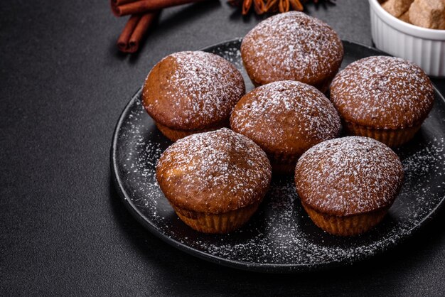 Beautiful delicious cupcakes with cocoa and raisins on a black concrete background Time to drink tea