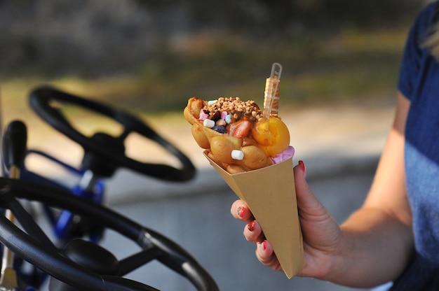 Beautiful delicious ice cream in a cone cone is held in the hands of a girl close up.