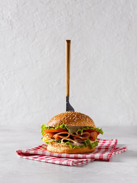 A beautiful and delicious sandwich is punctured with a knife Its lying on a  napkin Light background