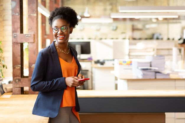 Beautiful designer. Beautiful African-American designer wearing stylish necklace holding phone