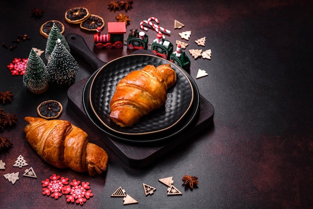 Beautiful different Christmas decorations and croissant on a brown concrete table