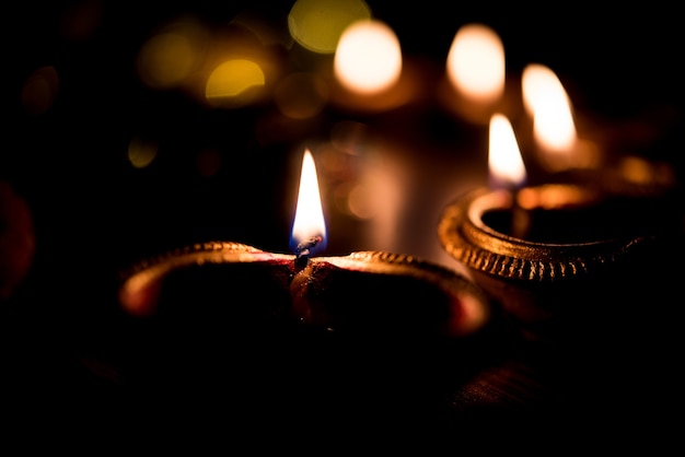 Beautiful Diwali diyas at night with flowers, lighting series and gifts, moody scene