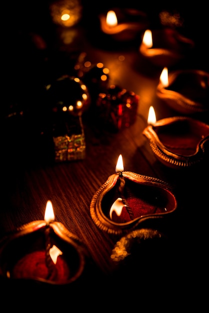 Beautiful Diwali diyas at night with flowers, lighting series and gifts, moody scene