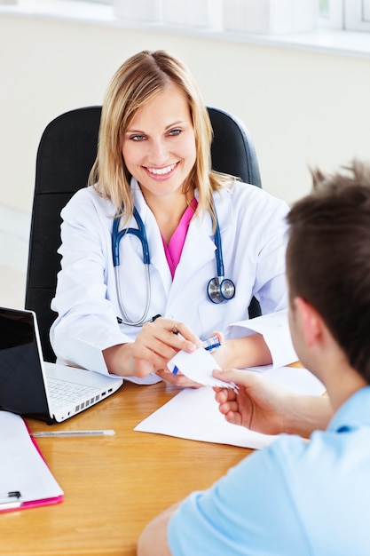 Beautiful doctor giving a prescription to her male patient sitting in her office