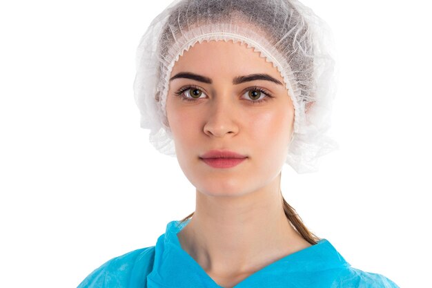 의학 모자를 쓴 아름다운 의사가 흰색 배경에 서 있습니다.