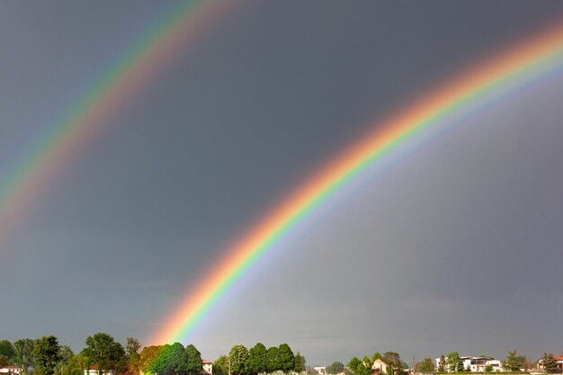 A beautiful double colorful rainbow against the background of a dangerous stormy sky