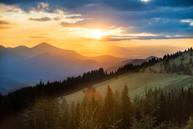 Beautiful dramatic sunset in the mountains. Landscape with sun shining through orange clouds