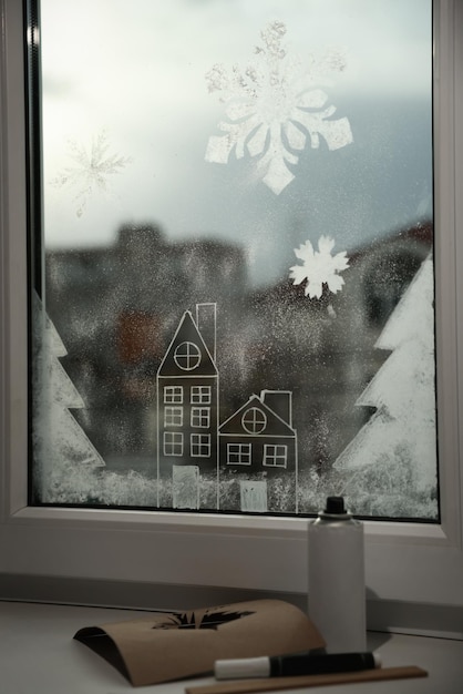 家のクリスマスの装飾の窓に人工雪で作られた美しい絵