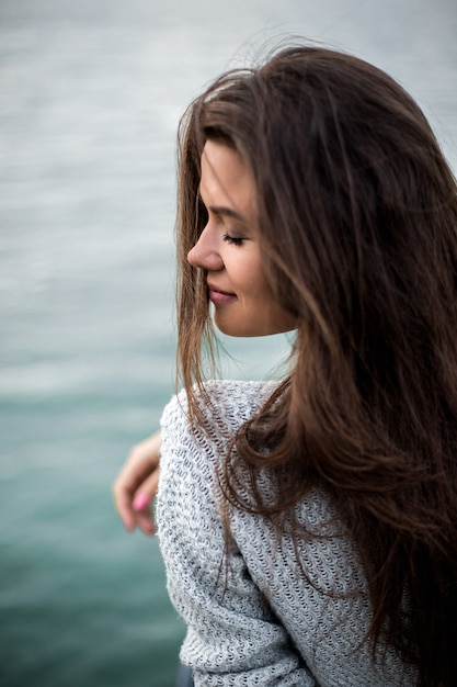 Beautiful dreaming woman sitting by the lake.