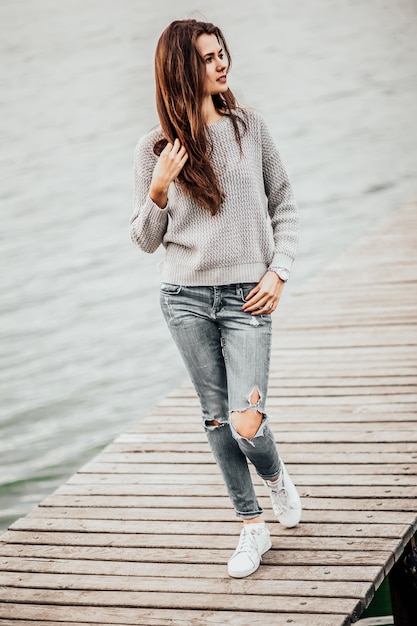 Foto bella donna che sogna a piedi sul molo sul lago.